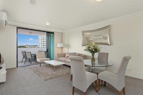 a living room with a couch and a table and chairs at Republic Apartments Brisbane City in Brisbane