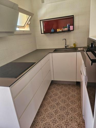 une cuisine avec des armoires blanches et un évier dans l'établissement 3P Vue Mer Centre Ville, à Antibes