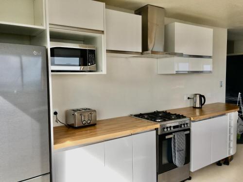 a kitchen with white cabinets and a stove and a microwave at 90 Mile Paradise Ahipara in Ahipara