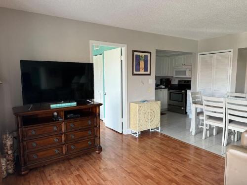 a living room with a flat screen tv on a wooden dresser at Crescent Arms Condominiums in Siesta Key
