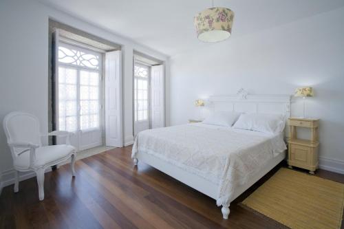 a white bedroom with a white bed and a chair at Mercearia da Vila in Ponte de Lima