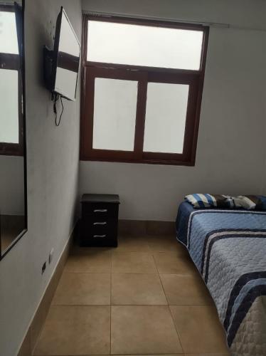 a bedroom with two windows and a bed and a tv at Hostal Lobitos in Cerro Azul