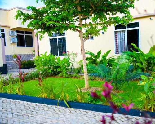 a garden in front of a house with a tree at Cherryhomes at Mbezi Juu in Dar es Salaam