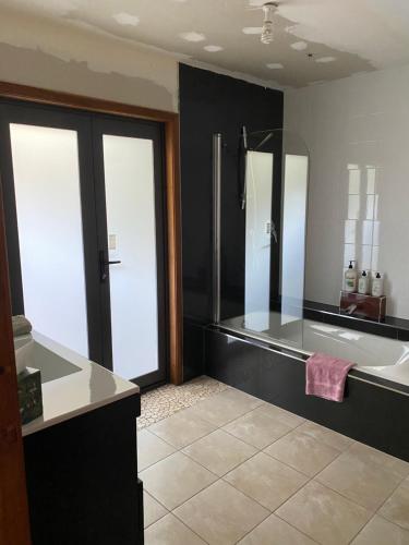 a bathroom with a tub and a sink and a mirror at 90 Mile Paradise Ahipara in Ahipara