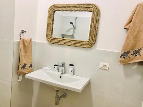 Un baño con un lavabo y un espejo en la pared. en Cosy and Comfy Apartment 2 min walk to the beach, en Sarandë