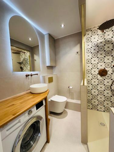 une salle de bain avec machine à laver et toilettes dans l'établissement le petit mouillage, à 100 m de la plage, à Grimaud