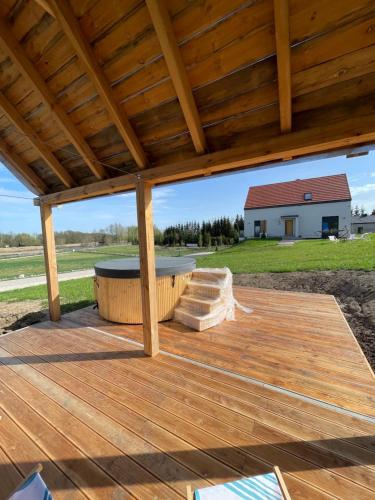 a wooden deck with a hot tub and a wooden roof at Rumiane pola - stodoła na Mazurach z widokiem na jezioro in Brajniki
