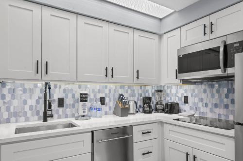 a kitchen with white cabinets and a sink and a microwave at Spacious 1BR near Universal I-Drive in Orlando