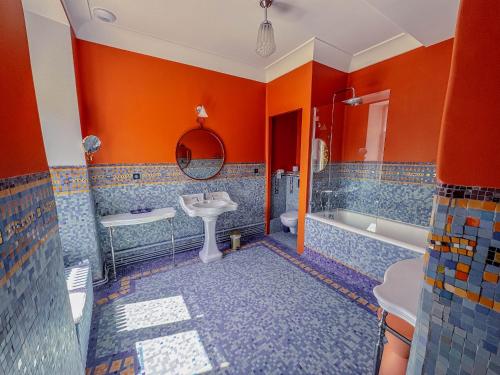 bagno con pareti arancioni, lavandino e vasca di Domaine de Kerrosen à proximité du port de Dinan, sur la Rance a Taden