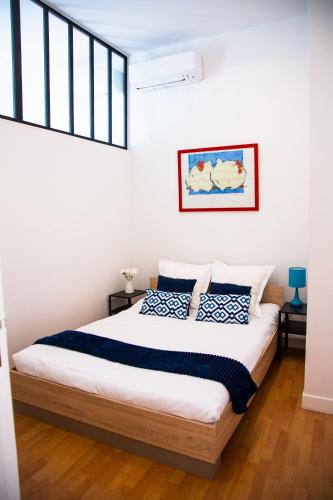 une chambre avec un grand lit avec des oreillers bleus et blancs dans l'établissement Appartement 3p Paradis 5 minutes de la plage AC, à Nice