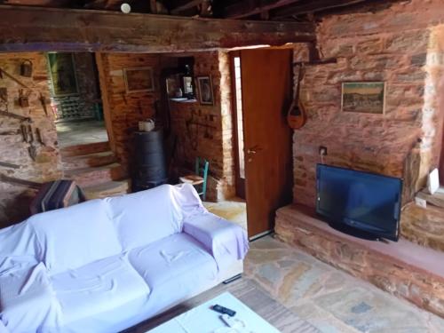 a living room with a couch and a tv at Traditional stone house in Pelion in Rodhiás