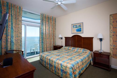 a bedroom with a bed and a window with a balcony at Holiday Sands at South Beach in Myrtle Beach