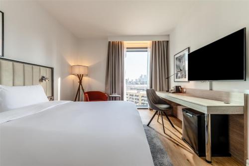 a hotel room with a bed and a desk with a television at Radisson Hotel Manchester City Centre, A Verified Net Zero Hotel in Manchester