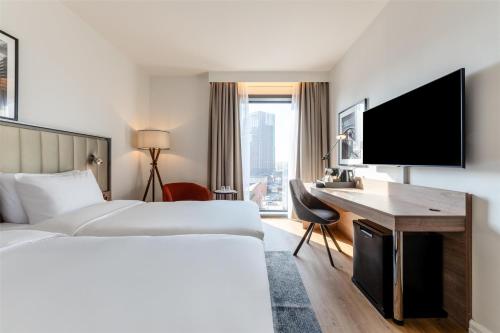 a hotel room with a bed and a desk and a tv at Radisson Hotel Manchester City Centre, A Verified Net Zero Hotel in Manchester