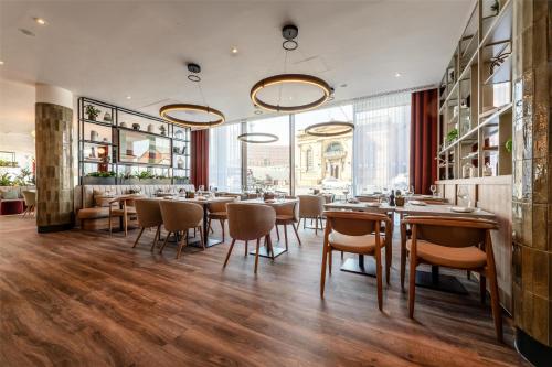 a restaurant with tables and chairs and a large window at Radisson Hotel Manchester City Centre, A Verified Net Zero Hotel in Manchester