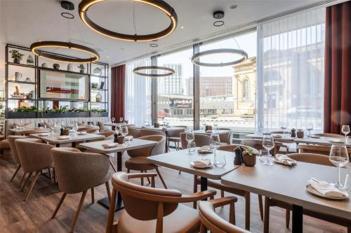 a restaurant with tables and chairs and a large window at Radisson Hotel Manchester City Centre, A Verified Net Zero Hotel in Manchester