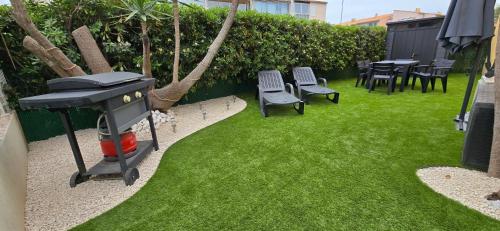 d'un jardin avec barbecue, chaises et pelouse dans l'établissement Appartement agde - terrasses de la plage, au Cap d'Agde