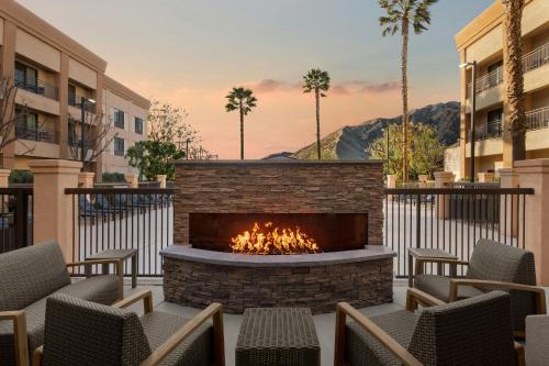 an outdoor patio with a fireplace and chairs and palm trees at Courtyard by Marriott Santa Clarita Valencia in Valencia