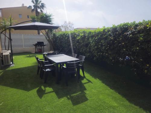 - une table et des chaises avec un parasol dans la cour dans l'établissement Appartement agde - terrasses de la plage, au Cap d'Agde