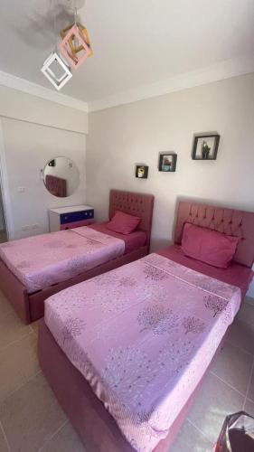 two beds in a room with pink sheets at فيلا دوبلكس في العين السخنة في قرية بلو باي أسيا عروس السخنة in Ain Sokhna