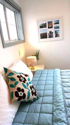 a bedroom with a bed with a blue comforter and two windows at Lush & Co Auckland Bed & Breakfast in Auckland