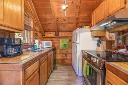 a kitchen with wooden cabinets and a white refrigerator at Cute Studio Cabin! Views! Private. Hot Tub. Relax! in Sevierville