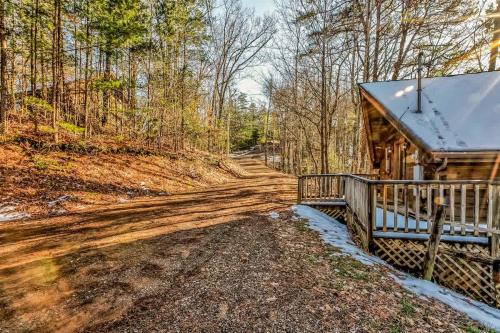 a log cabin in the woods with a dirt road at Cute Studio Cabin! Views! Private. Hot Tub. Relax! in Sevierville