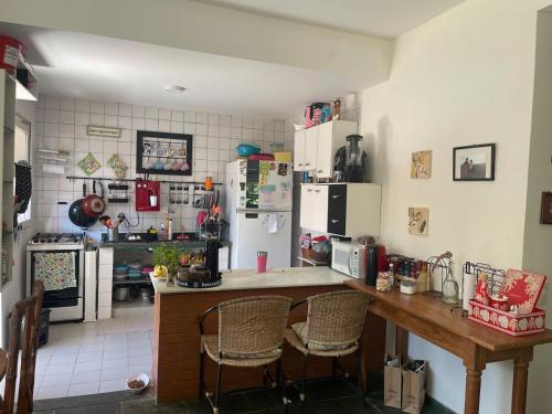 eine Küche mit Theke mit Stühlen und Kühlschrank in der Unterkunft Casa perto do mar, conforto em meio a natureza in Búzios