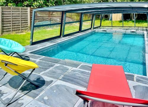 une piscine avec deux chaises et une table dans l'établissement Villa Leonic - Piscine et Jacuzzi, à La Forêt-Fouesnant