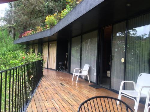 a patio with white chairs on a wooden deck at Cabañas el Retorno in Guatapé