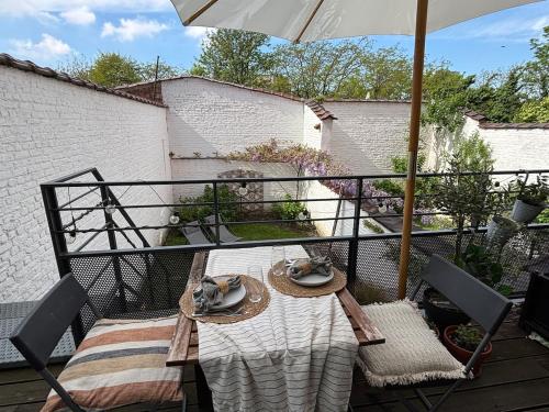 un tavolo e delle sedie su un balcone con un ombrellone di Appartement lumineux avec jardin proche du centre a Bruxelles
