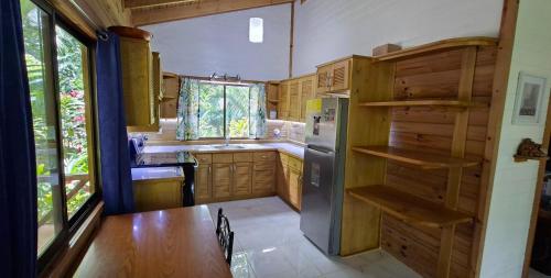 a kitchen with wooden cabinets and a stainless steel refrigerator at Cabinas Costa Tropicana in Uvita