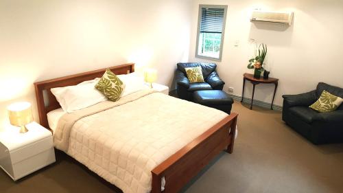 a bedroom with a large bed and a chair and a chair at Lush & Co Auckland Bed & Breakfast in Auckland