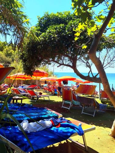 a beach with tables and chairs and umbrellas at Rooms del Moro in Patù
