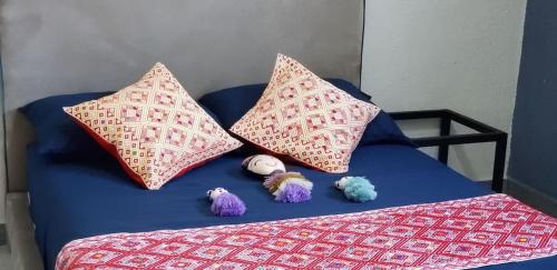 a blue bed with two pillows and stuffed animals on it at 3 BR house 1AC y garage in Parque de la Marimba in Tuxtla Gutiérrez