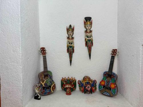 a wall with four guitars and masks on it at 3 BR house 1AC y garage in Parque de la Marimba in Tuxtla Gutiérrez
