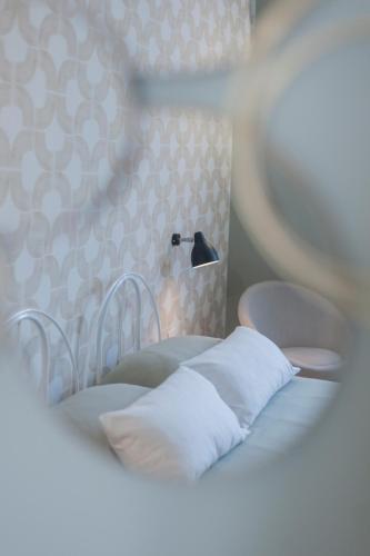 a bed with white pillows and a lamp on it at Eleganza e comfort in centro in Ivrea