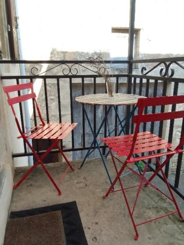 - deux chaises rouges et une table sur un balcon dans l'établissement Gîte Dornecy, à Dornecy