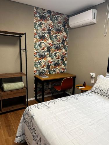 a bedroom with a bed and a desk and a wall at Guaja 745 - Apartamento Marie Lili in Belo Horizonte