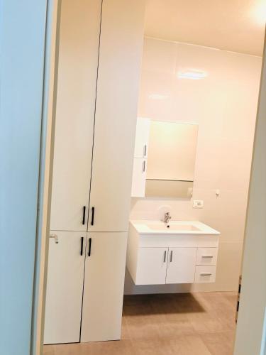 a white bathroom with a sink and a mirror at Apartment Sun&Sea Durres by Sasha in Durrës