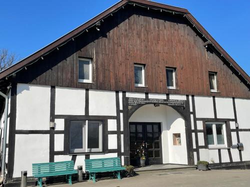 a building with two green benches in front of it at Hof Uffenbeck - Apartment 5, auf dem Land in Melle