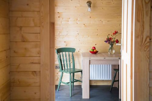 a wooden room with a table and a green chair at The Stable at CasaClarig - West Cork Cabin with Sauna in Ballydehob