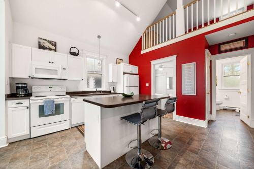 a kitchen with white cabinets and a red wall at The Tree Frog - 12 Pine Forest in Cherry Valley