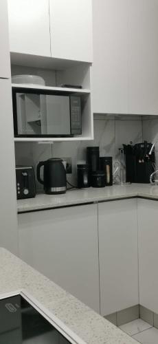 a kitchen with white cabinets and a microwave at Sandhurst Luxury Accommodation Self-Catering Suites in Pietermaritzburg in Pietermaritzburg