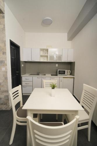 a kitchen with a white table and white chairs at Suites Castello in Bar
