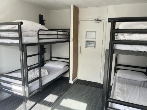 a dorm room with three bunk beds and a hallway at Lulworth Hostel in West Lulworth