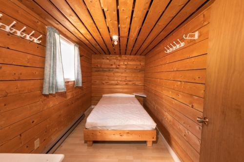 a small room with a bed in a wooden cabin at Chalet de la Berge 2 in Murdochville