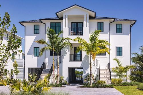 a white building with palm trees in front of it at Waterfront Luxury Home - Tidelands House in Key West