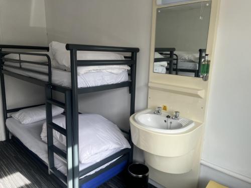 a bathroom with a sink and a shelf with a mirror at Lulworth Hostel in West Lulworth
