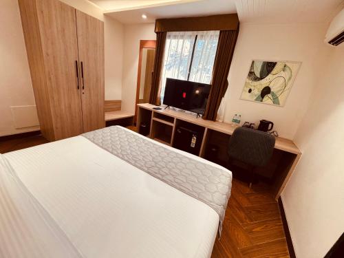 a bedroom with a bed and a desk with a television at Hotel Mumbai House Vijay Nagar Nr Brilliant Convention Center in Indore